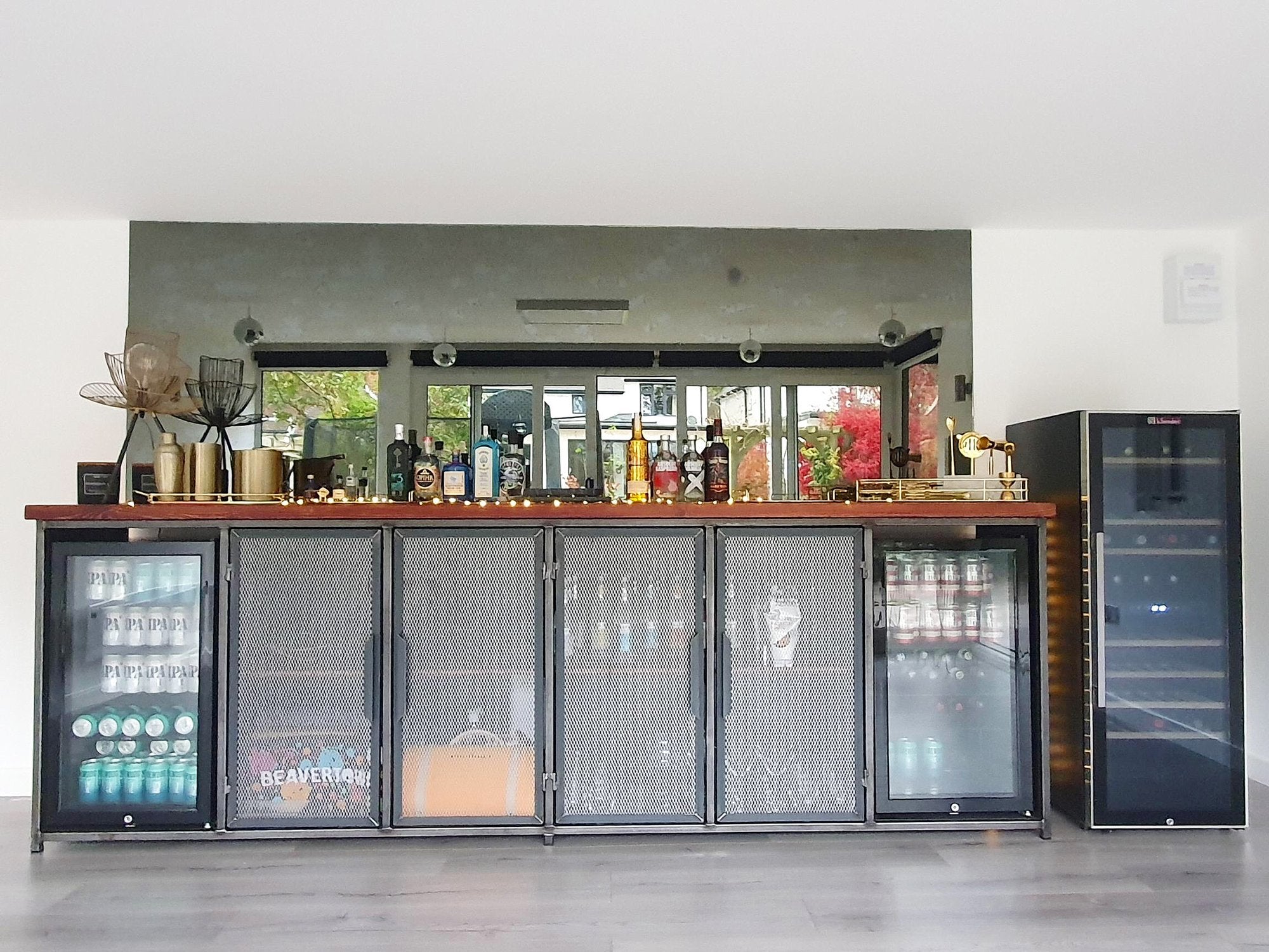 An impressive home bar setup that seamlessly blends an industrial theme and a beer drinks cooler