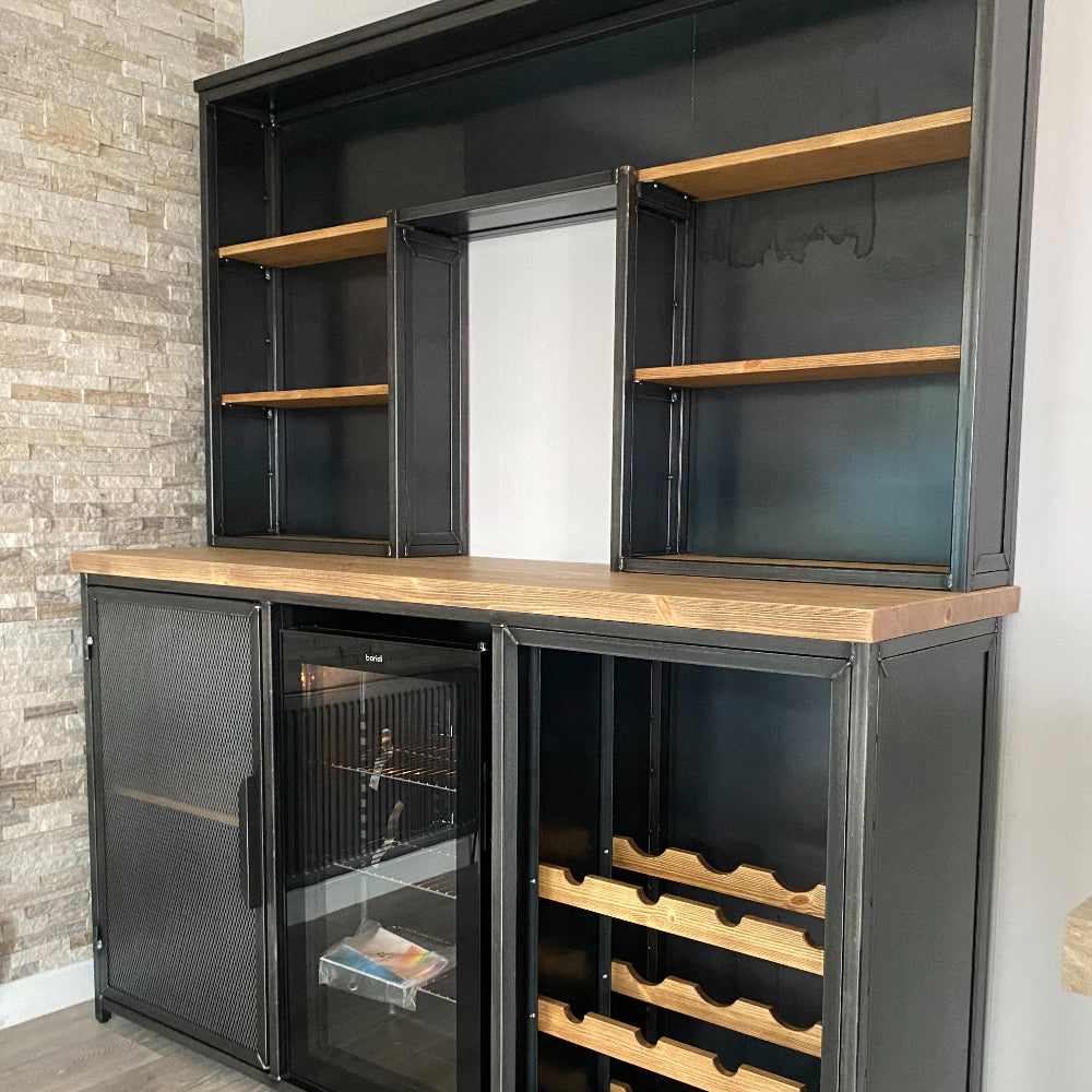 Modern kitchen cabinet with wine storage and refrigerator against a brick wall.