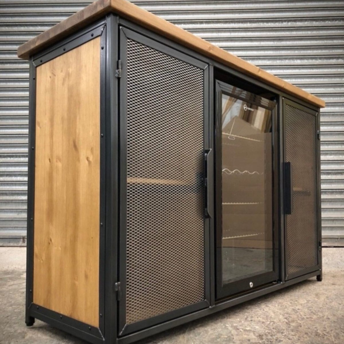 Close-up of wooden drinks cabinet showing integrated fridge door and industrial steel frame