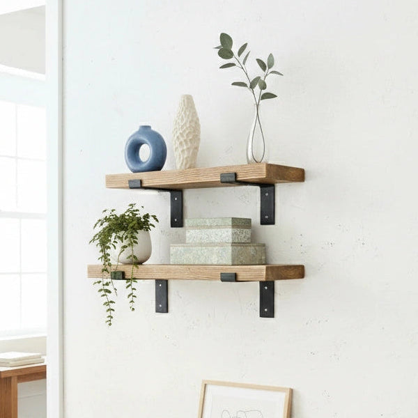 Wooden shelves with decorative items on a white wall in a room with a desk and plant.