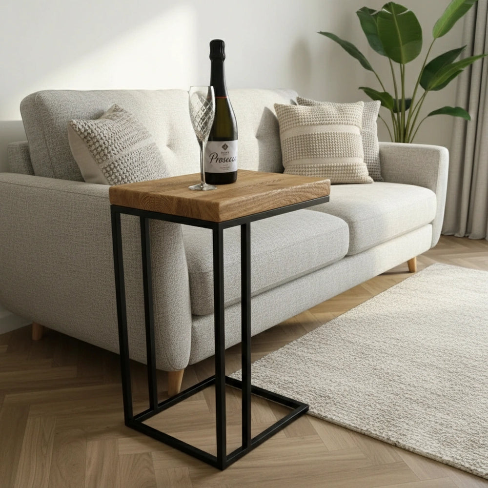 Wooden side table with a bottle of wine and glass on a sofa in a living room.