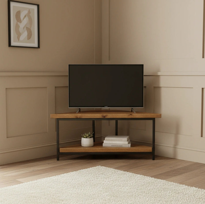 Wooden TV stand with a television and decorative items against a beige wall.
